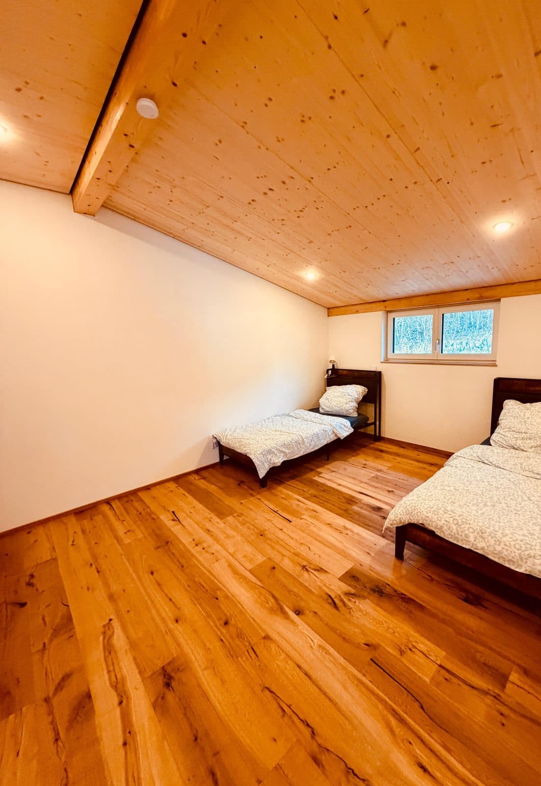 Helles Dachgeschoss-Schlafzimmer mit Holzdecke, Eichenboden und zwei Betten